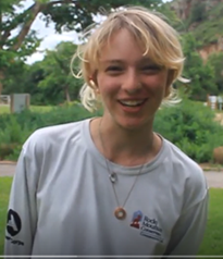 A young woman smiling in front of a tree.