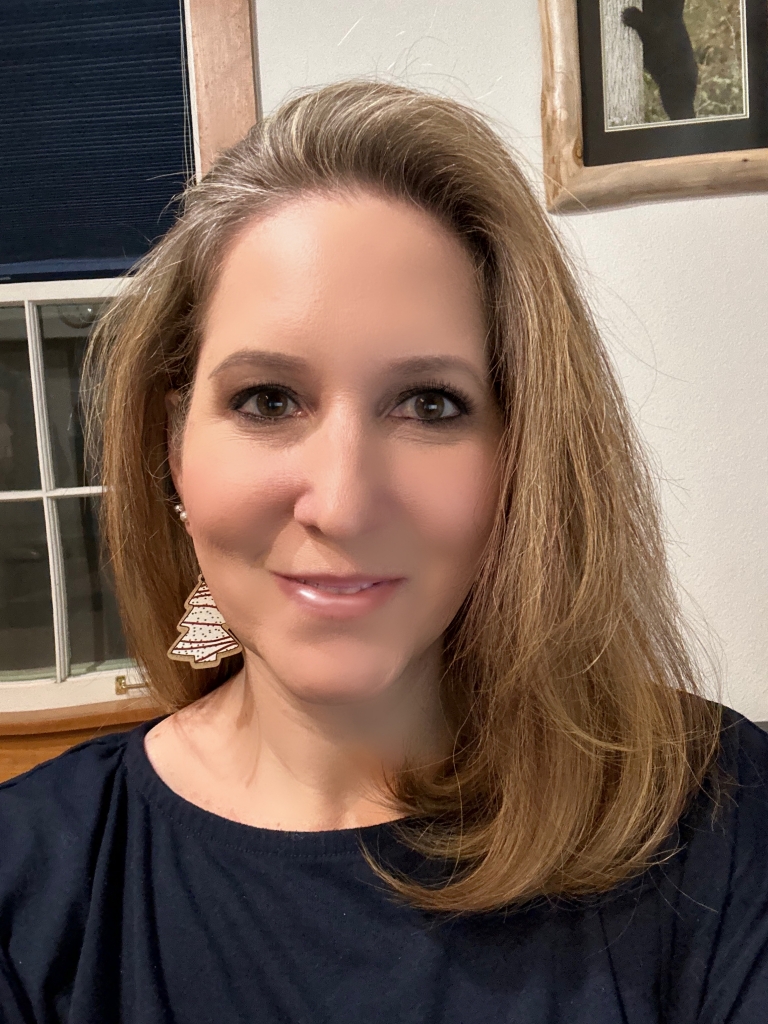 A woman in a blue shirt is smiling at the camera.