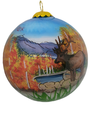 Ornament featuring a fall scene with a deer by a pond, framed by autumn trees and mountains in the background, named RMNP Fall Scene Glass.