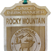 Junior Ranger Badge An ornament, named the "RMNP Junior Ranger Badge," features a wooden design with the words "Junior Park Ranger Rocky Mountain National Park" and an engraved image of a deer and trees.