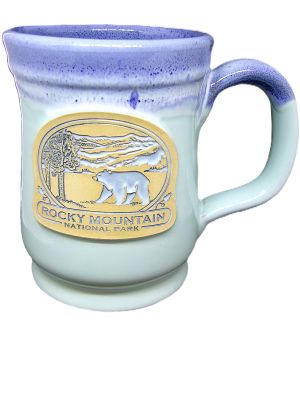 The Deneen RMNP Pepin Black Bear mug features a ceramic build with a purple rim and a gold emblem showcasing the Rocky Mountain National Park, complete with a bear and trees.