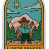 JR Ranger Bear Sticker Illustration of a bear in ranger outfit with mountains, trees, and a sun. Text: "Junior Ranger Rocky Mountain National Park." Product: Sticker - RMNP Junior Ranger Bear.