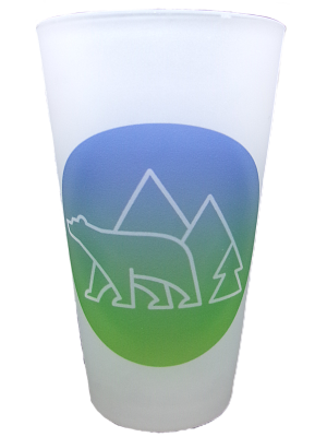 The Glass - RMNP Pint Bear Logo features a white outline of a bear, pine tree, and two mountains on a frosted cup with a blue and green circular background.