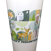 A pint glass named "RMNP Pint Mod Collage" showcases stylized illustrations of forest animals and plants inspired by Rocky Mountain National Park.