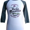 A white and green raglan long sleeve shirt featuring "Colorado Rocky Mountain National Park" and a graphic of mountains, trees, and a lake on the front. Product: Long Sleeve Shirt - RMNP Elk View.