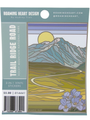 Sticker - Trail Ridge Road 2-in-1: Illustrated sticker showcasing Trail Ridge Road in Rocky Mountain National Park, with a winding road, mountains, sun, and purple flowers; product info is included on the packaging.
